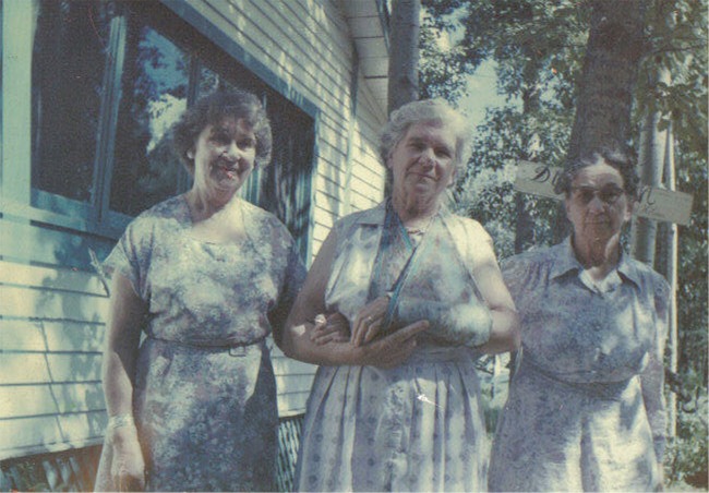 A group of women standing outside a house

Description automatically generated