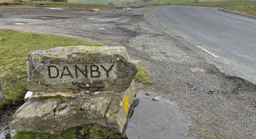 A stone sign on a road

Description automatically generated