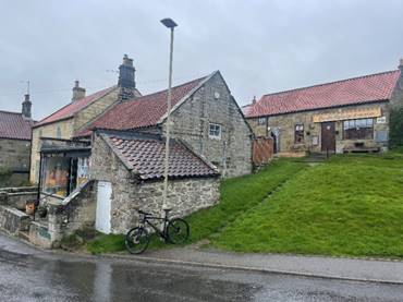 A stone building with a green lawn and a bicycle parked on the side of it

Description automatically generated