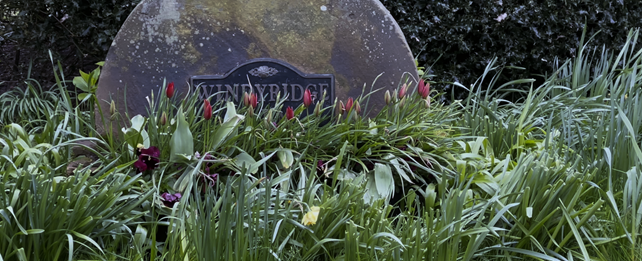 A stone with flowers around it

Description automatically generated