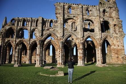 A person taking a picture of an old building

Description automatically generated