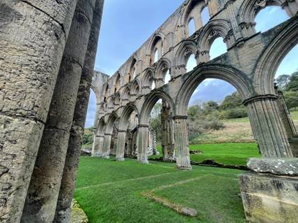 A stone building with arches and grass

Description automatically generated