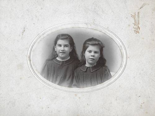 A couple of young girls in a white oval frame

Description automatically generated