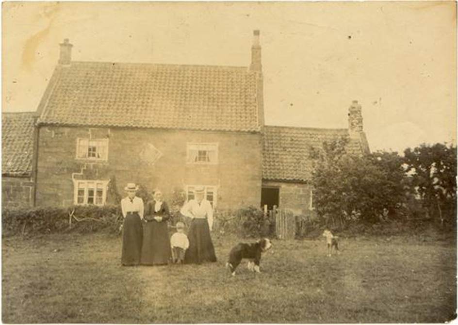 A group of people and dogs in front of a house

Description automatically generated