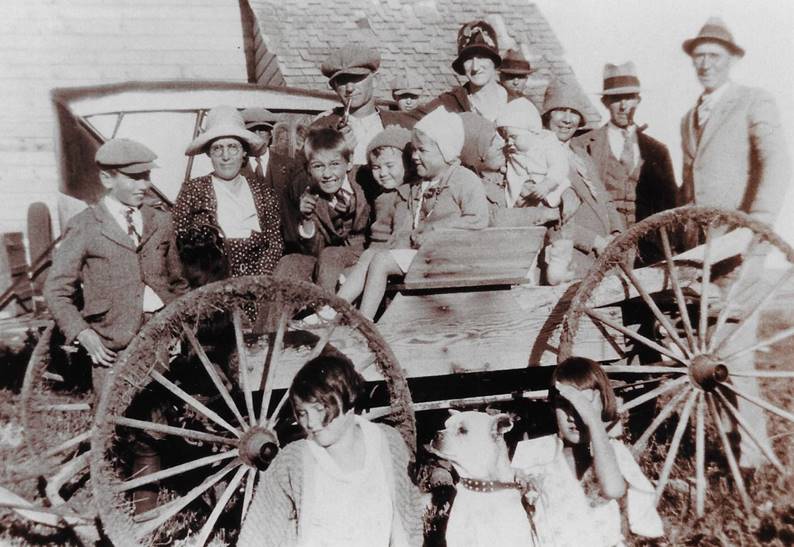 A group of people standing in front of a wagon

Description automatically generated