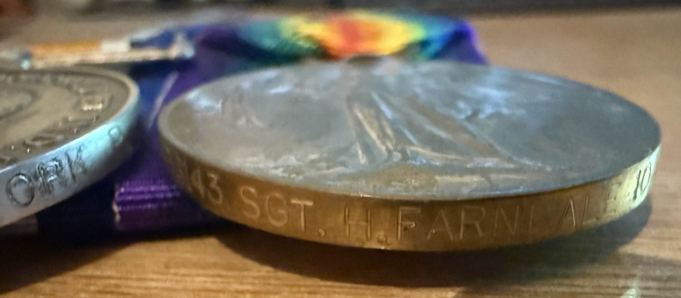 A silver coin with a rainbow ribbon

Description automatically generated