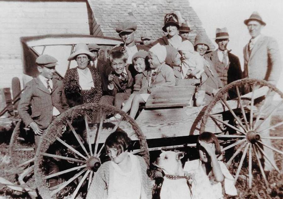 A group of people standing in front of a wagon
Description automatically generated
