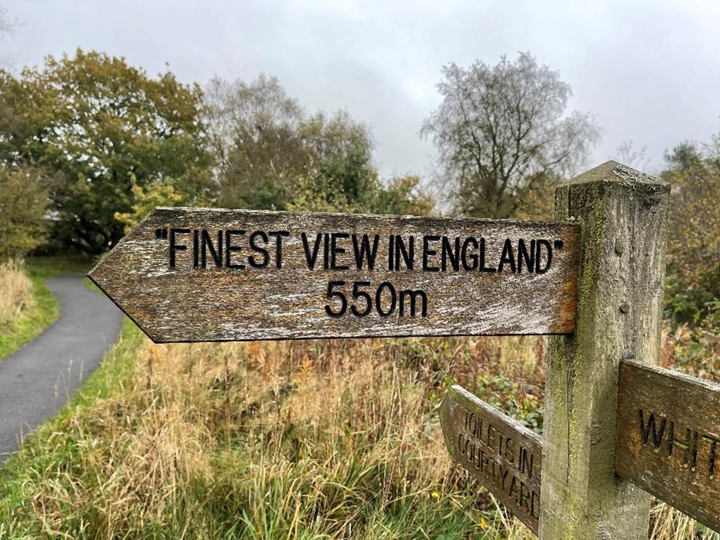 A sign post with a road and trees
Description automatically generated