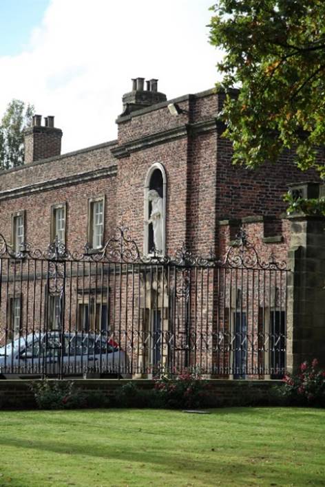 A brick building with a fence

Description automatically generated
