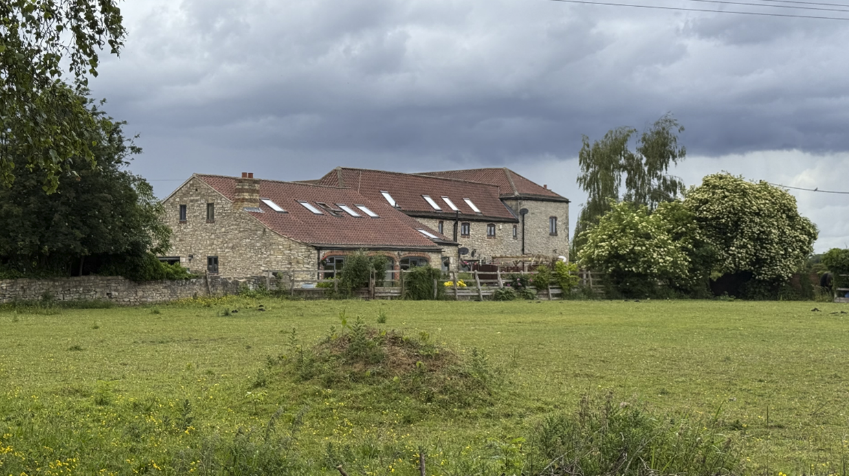 A large stone building with a fence and grass field

AI-generated content may be incorrect.