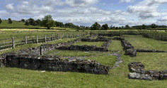 A stone wall in a field with Vindolanda in the background

AI-generated content may be incorrect.