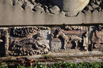 A stone carving of horses and a person

Description automatically generated