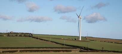 A wind turbine in a field with Codrington Wind Farm in the background

Description automatically generated