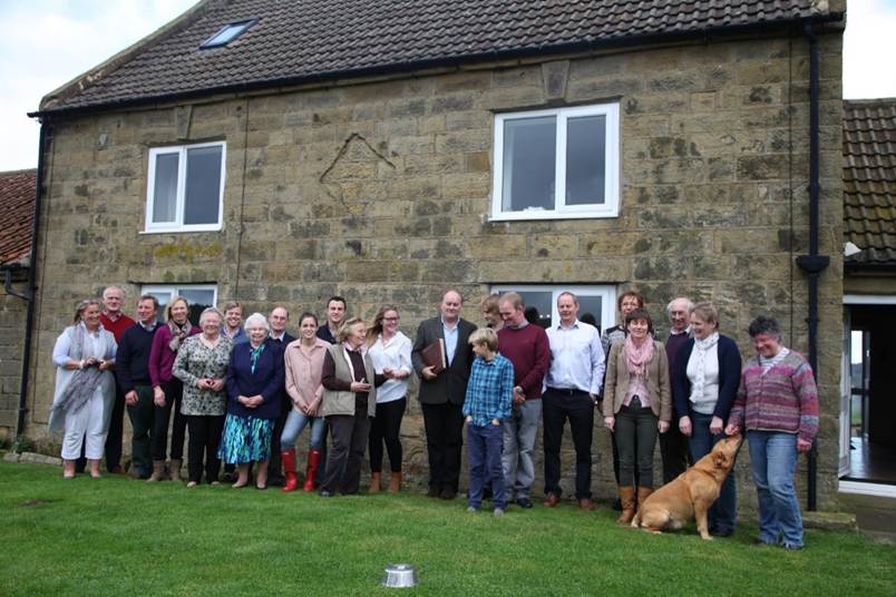 A group of people standing in front of a house

Description automatically generated
